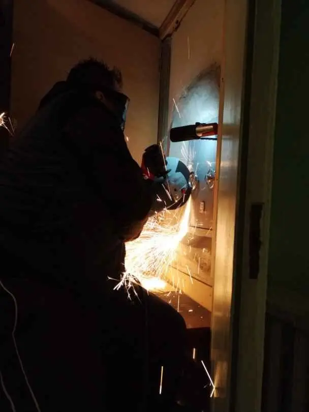 Iván trabajando de noche con una radial junto a una puerta, entre chispas